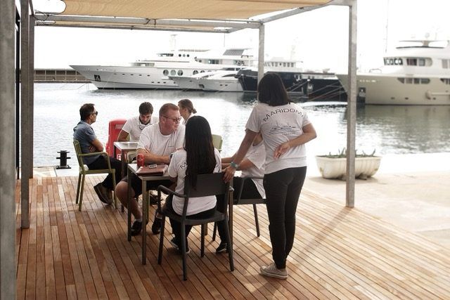 Crew members chatting on the wooden terrace of the Sirius Club, overlooking the berths