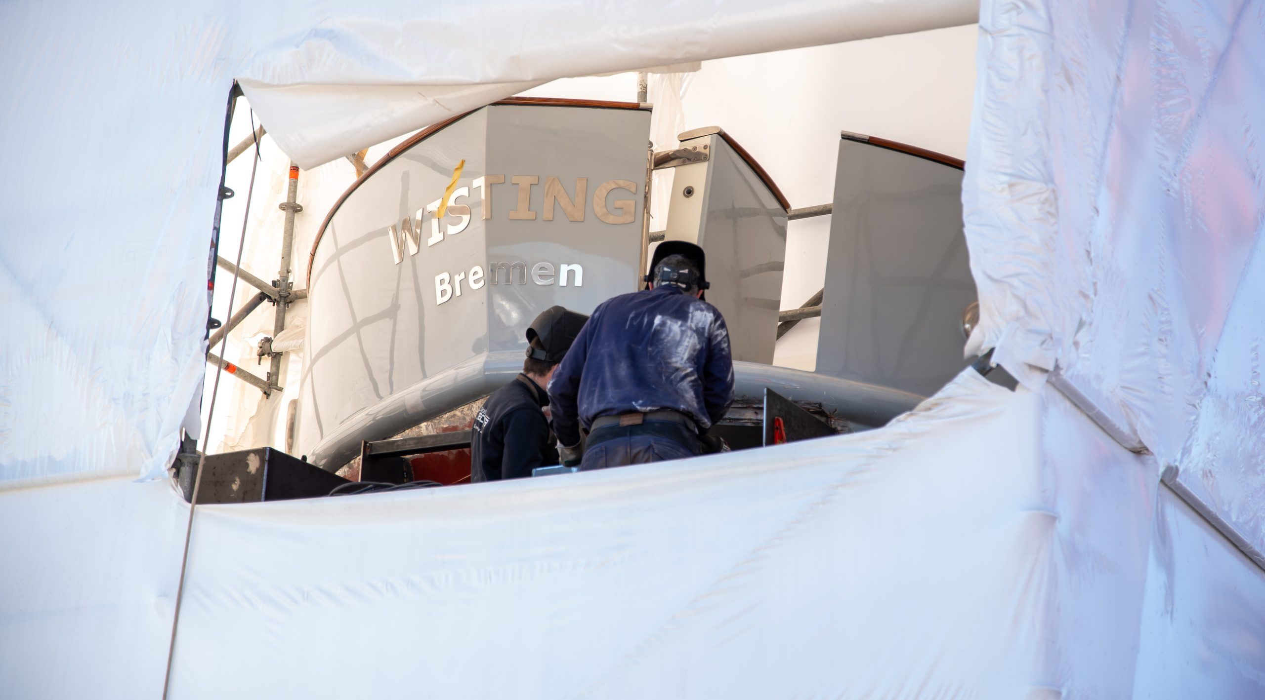 Worker inside a protective tent over a yacht during a refit