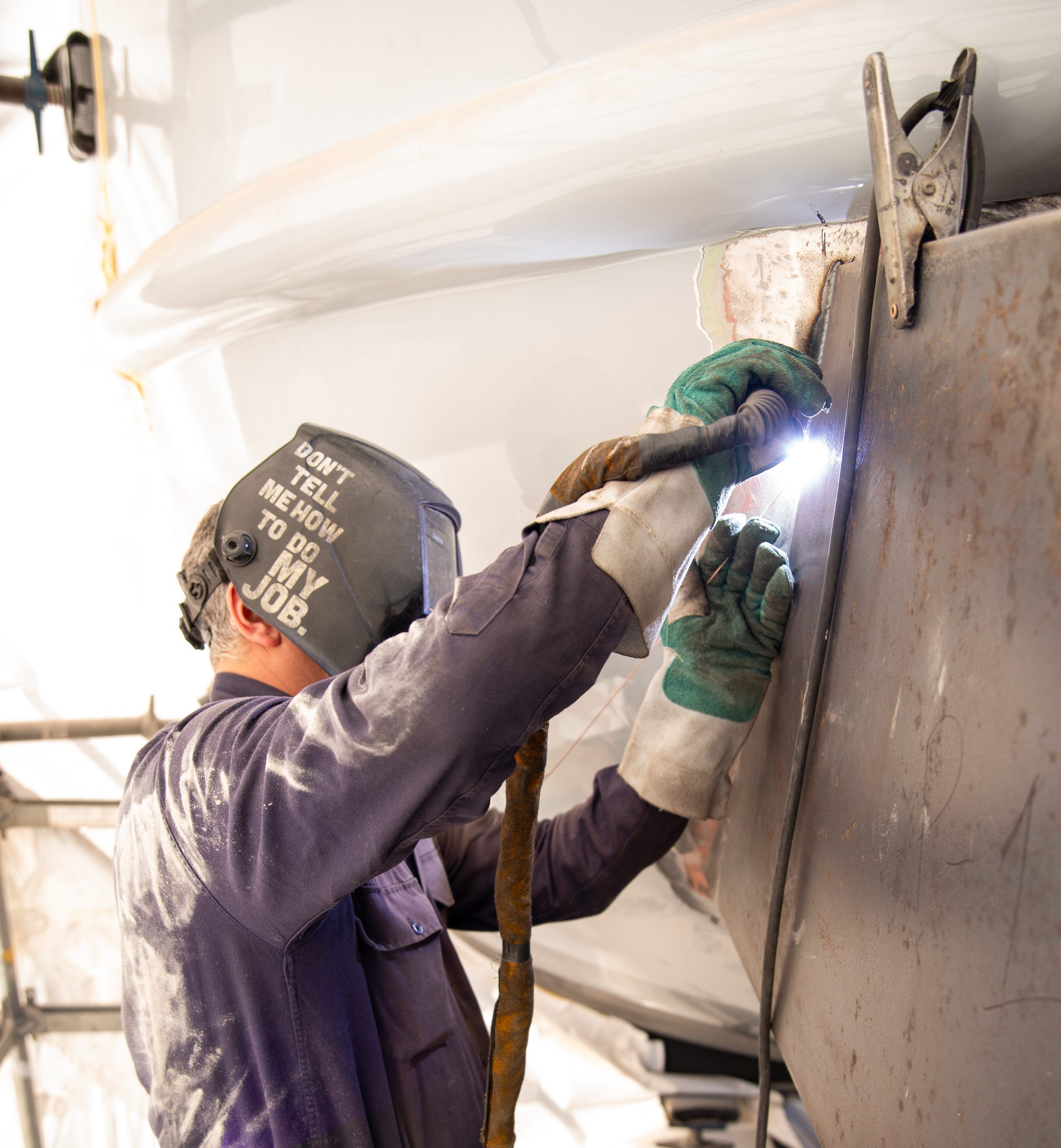 Welder working on a yacht's metal hull