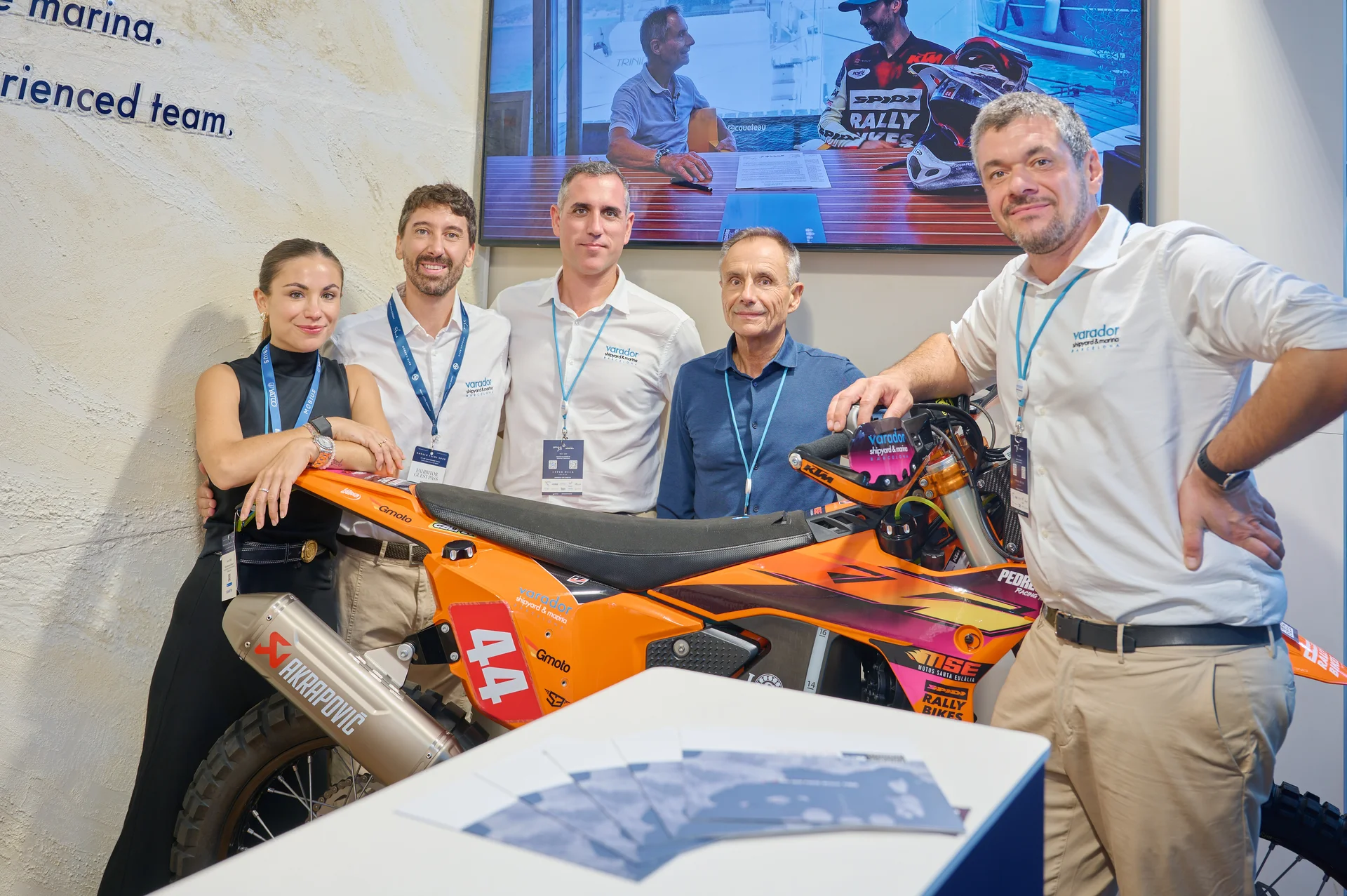Equipo de Varador 2000 junto a la moto de rally con los colores del astillero en el stand del Monaco Yacht Show